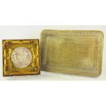 AN INDIAN BRASS REPOUSSÉ TRAY AND A DECORATIVE RESIN PLAQUE, GILT FRAME