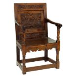 A CHARLES II OAK PANEL BACK ARMCHAIR CARVED WITH LUNETTES AND GUILLOCHE