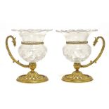 A PAIR OF VICTORIAN GILT BRASS AND CUT GLASS EAGLE HEADED SINGLE HANDLED VASES BY F & C OSLER,