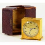 A ZENITH GILT BRASS MINIATURE CLOCK, THE TIMEPIECE IN REEDED SQUARE CASE, LEATHER TRAVELLING CASE