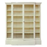 A GEORGE III STYLE WHITE PAINTED BREAKFRONT BOOKCASE ENCLOSED BY FOUR GLAZED DOORS
