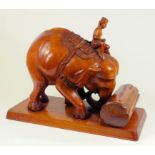 AN INDIAN CARVED WOOD SCULPTURE OF AN ELEPHANT PUSHING A LOG