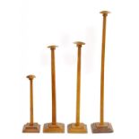 FOUR EARLY 20TH CENTURY OAK MILLINERS HAT STANDS ON STEPPED SQUARE BASE