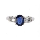 A SAPPHIRE AND DIAMOND RING  with oval sapphire and baguette diamonds to the shoulders, in white