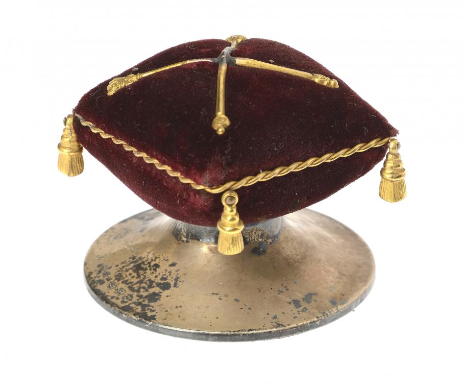 AN UNUSUAL GEORGE V COMMEMORATIVE SILVER AND GILTMETAL TRIMMED MAROON VELVET PIN CUSHION 4.5cm h, by