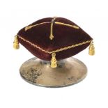 AN UNUSUAL GEORGE V COMMEMORATIVE SILVER AND GILTMETAL TRIMMED MAROON VELVET PIN CUSHION 4.5cm h, by