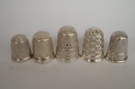 A collection of five silver thimbles, on