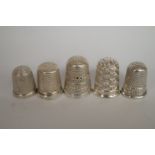 A collection of five silver thimbles, on