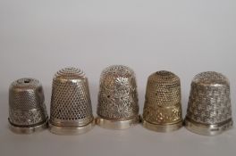 A collection of five silver thimbles, on