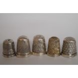 A collection of five silver thimbles, on