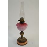 A brass oil lamp with pink glass shade