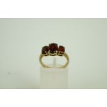 A three stone garnet 9ct gold ring, fing