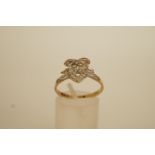 A diamond lovers heart 9 carat gold ring, the open heart motif with an ribbon bow surmount, set