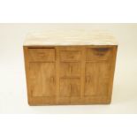 An oak Art Deco chest with pink marble top above an arrangement of five drawers and two cupboard