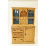 A pine dresser the top with two glazed doors and a arrangement of drawers above one cupboard door