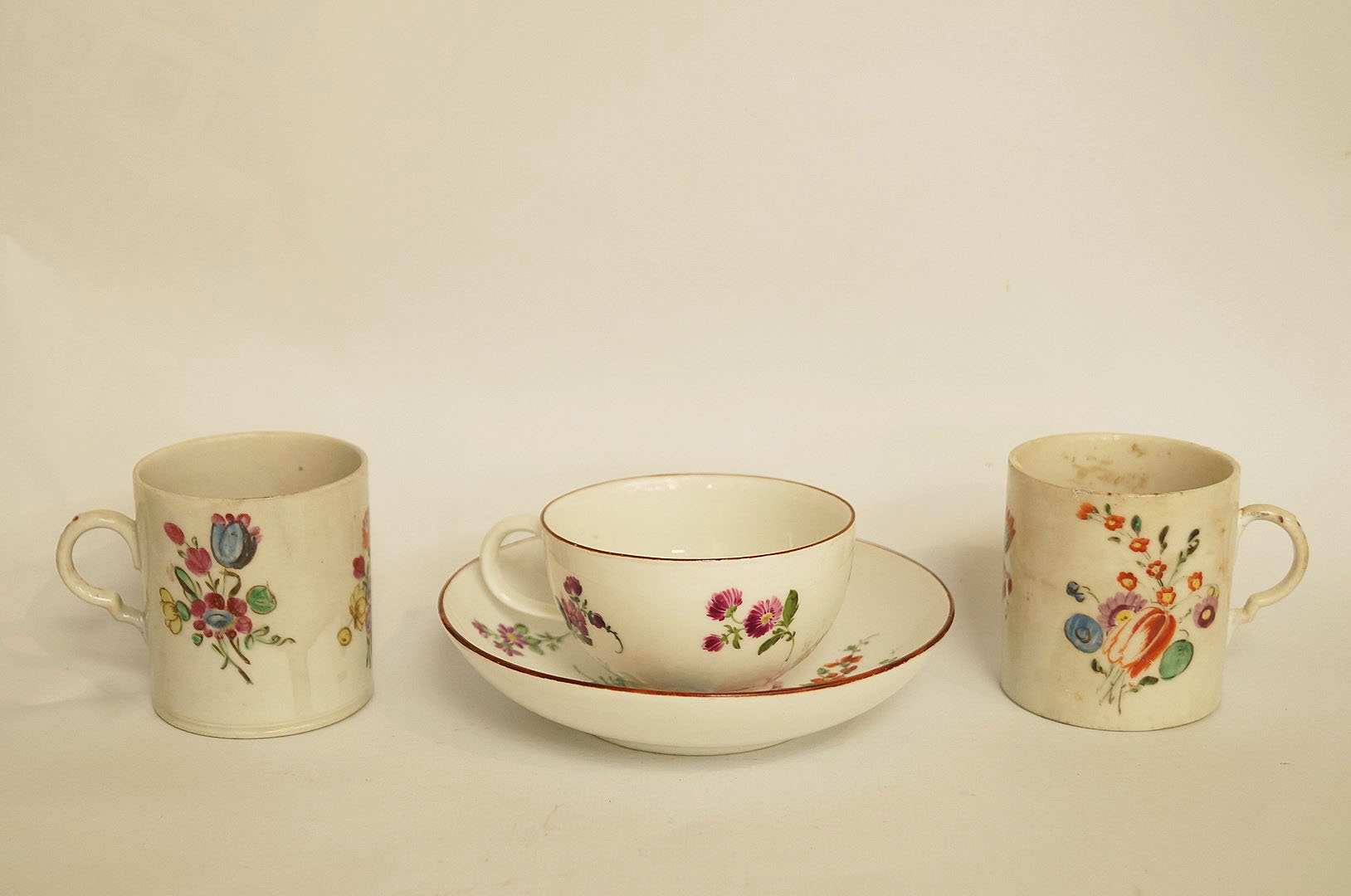 A 19th century Meissen tea cup and saucer painted with European flower sprays within iron red rims,