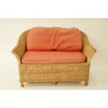 A Wicker two seat sofa with two loose cushions, W 131cm