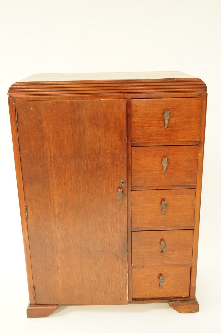 A mid 20th century oak compendium, with one cupboard door and five drawers, H 128cm W 90.5cm D 43cm