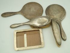 A silver backed three piece dressing table set, comprising of a hand mirror,