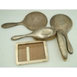 A silver backed three piece dressing table set, comprising of a hand mirror,