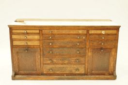 A 20th century oak dentist's cabinet with twelve small drawers and two drop door cupboards,