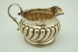 A Victorian silver cream jug with spirally reeded body and flared foot, by E.S. Barnsley & Co.