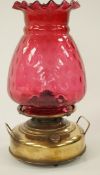 A late 19th century brass heater lamp, with double handles and dimpled glass shade,
