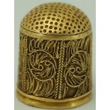 An early 17th century 18ct gold thimble, unmarked, with wire work decoration,