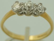A three stone diamond 18 carat gold ring, the uniform brilliant cuts, centre stone an old cut,