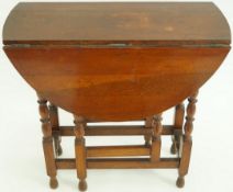 An oak oval drop leaf table with turned gate leg supports, height 73.5cm, width 92.