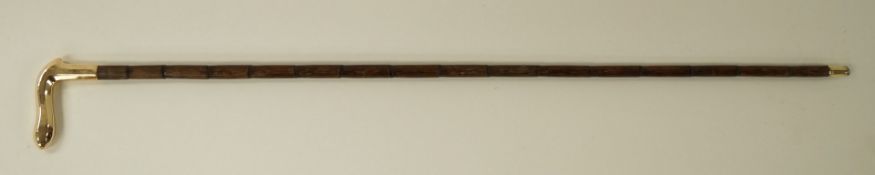 A bamboo walking cane with shaped brass hand grip,