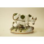 A late 19th century Staffordshire pottery figure of a cow and calf decorated with coloured enamels