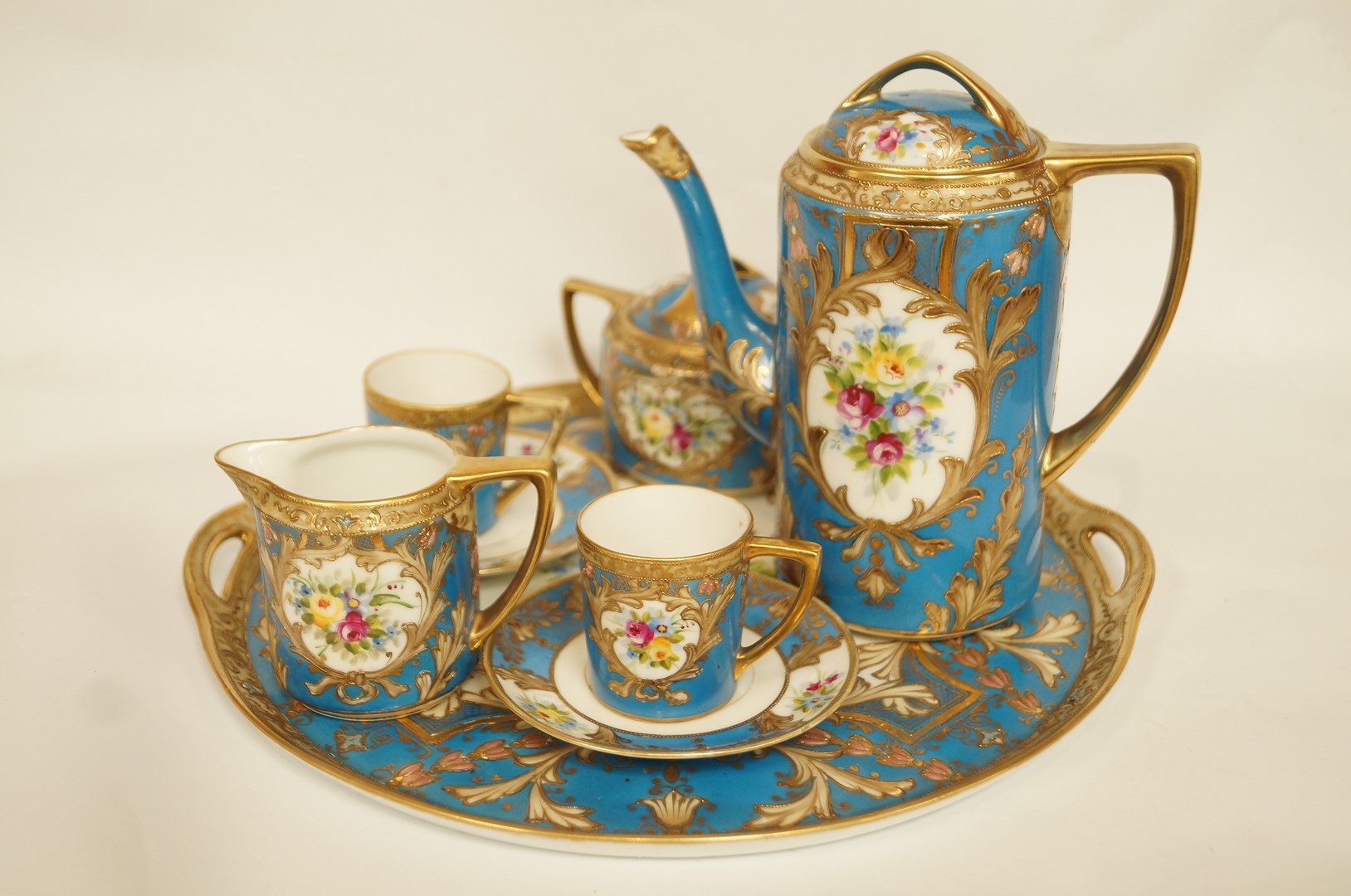 An early 20th century Noritake coffee set with gilt overlay decoration on a blue ground,