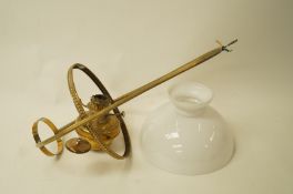 A hanging brass oil lamp with a white glass shade,