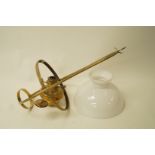 A hanging brass oil lamp with a white glass shade,