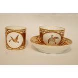 An early 19th century Paris porcelain trio each painted with a bird in flight on a striped gilt and