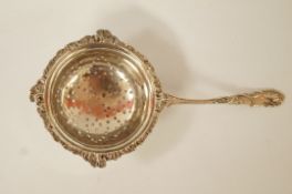 A silver tea strainer, by Mappin & Webb, decorated in the rococo style, 14.