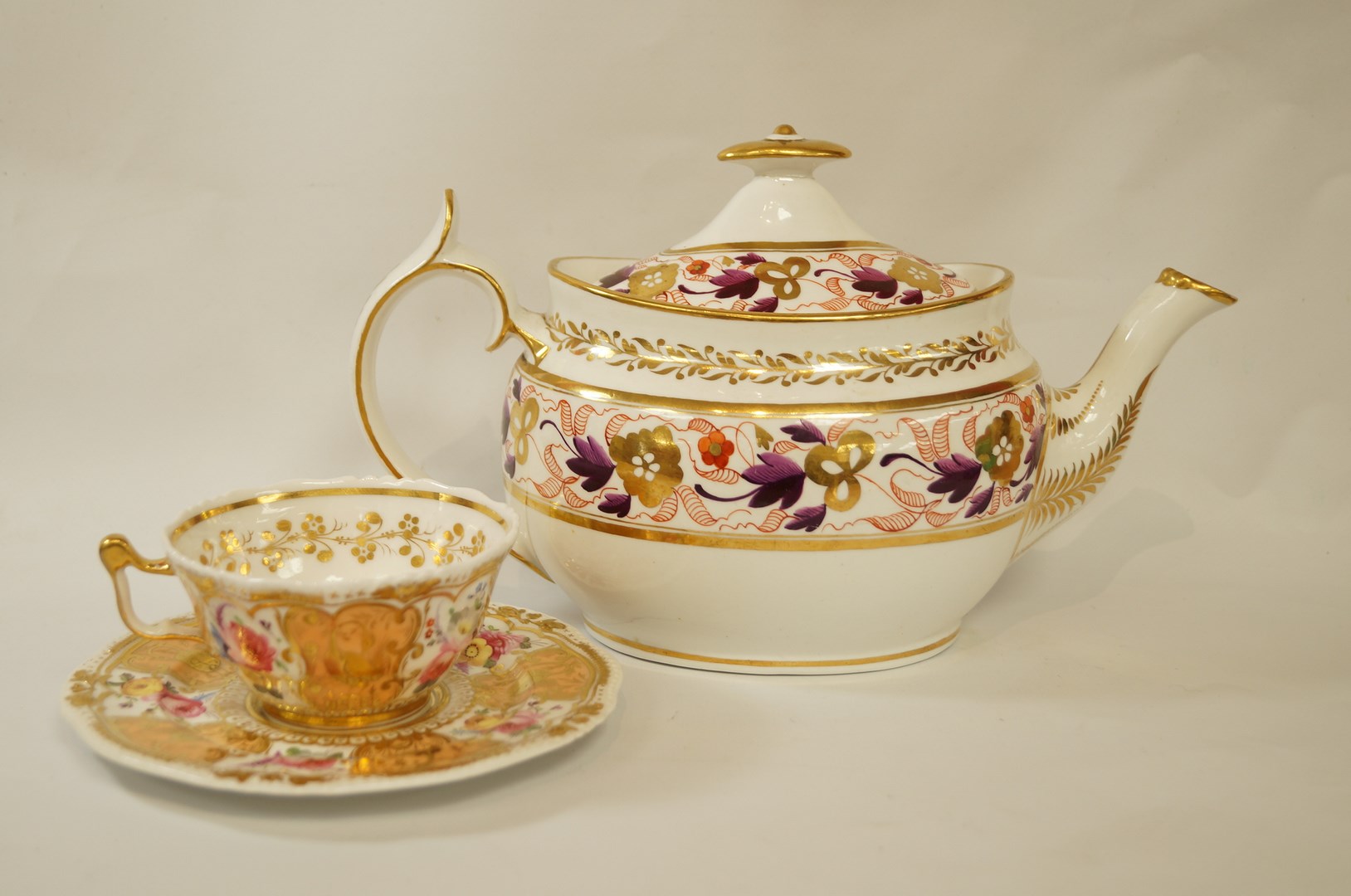 An early 19th century porcelain tea cup and saucer painted with flowers on a peach and gilt ground,