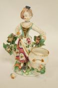 A Bow porcelain figure of a girl standing before a basket with bocage behind,