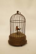 An early 20th century musical box in the form of a feathered bird in a cage with loop suspension