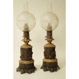 A pair of oil lamps with embossed bronzed and brass patinated bodies,