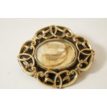 A Victorian mourning brooch, of oval shaped outline with scrolls against a black enamel ground,