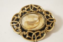 A Victorian mourning brooch, of oval shaped outline with scrolls against a black enamel ground,