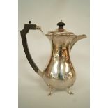 A silver hot water jug, Birmingham 1933, of baluster shape and on four supports,