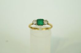 An emerald and diamond three stone ring, stamped '18ct' and 'Plat', the rectangular cut emerald, 5.