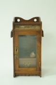 An early 20th century oak smokers cabinet, with single glass panel door,