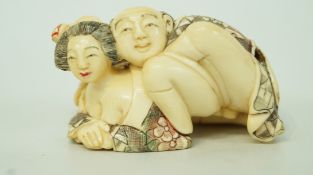 An early 20th century erotic ivory netsuke of two figures with engraved and dyed decoration,