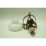 An early 20th century brass hanging oil lamp, with a white glass shade,