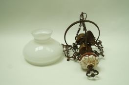 An early 20th century brass hanging oil lamp, with a white glass shade,