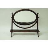 An Edwardian mahogany swing frame mirror with oval bevelled mirror plate,